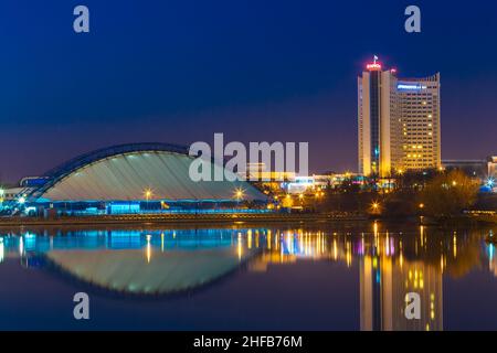 Hotelgebäude "Belarus" In Minsk, die Innenstadt von Nyamiha Nemiga Ansicht in alten Teil mit Swislotsch River, Belarus. Nacht-Szene-Straße Stockfoto