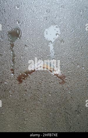 Unglücklich, von Hand gezeichnet verärgert unglückliche Gesichtsform wie Weinen auf gedämpfter Glasoberfläche oder Fenster mit Regentropfen an Regentagen. Regentropfen auf Fensterscheibe mit Stockfoto