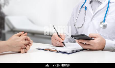 Ärzte und Patienten sitzen und sprechen mit dem Patienten über Medikamente. Unbekannter Mann Arzt und weibliche Patientin sitzen und sprechen bei der medizinischen Untersuchung in Stockfoto