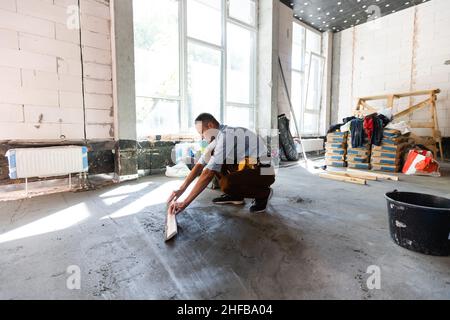 Arbeiter installieren den Boden. Reparaturman verfugen den Boden Stockfoto