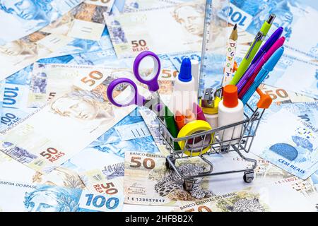 Schulbedarf mit Einkaufswagen, Bleistift, Stift, Lineal, Radierer und Schere, Mit Geldhintergrund, Schulbedarf Werbekonzept Stockfoto