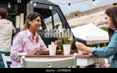 Glückliche Frauen, die auf dem Straßenmarkt essen Stockfoto