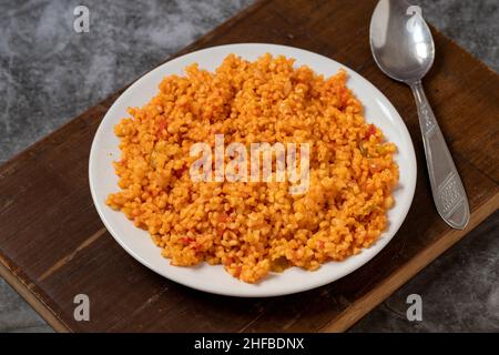 Bulgur Pilaf auf dunklem Hintergrund. Nahaufnahme des türkischen Essens Bulgur Pilav in einer Keramikplatte Stockfoto