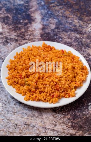 Bulgur Pilaf auf dunklem Hintergrund. Nahaufnahme des türkischen Essens Bulgur Pilav in einer Keramikplatte Stockfoto