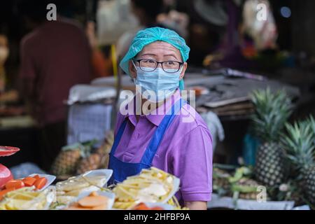 Porträt einer weiblichen Obstverkäuferin mit Schutzmaske am (Markt-)Talat Phlu im Thonburi-Gebiet von Bangkok, Thailand Stockfoto