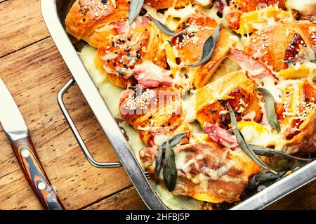 Gebackene Croissants mit Mozzarella-Käse, Speck, gekochtem Schweinefleisch und Salbei. Stockfoto