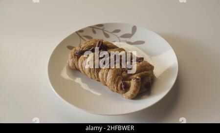 Mehrere Teller mit leckeren Backwaren in einer Reihe auf Holztisch platziert. Nahaufnahme von leckeren Brotprodukten auf weißem Tischhintergrund. Stockfoto