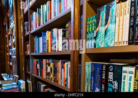 Porto, Portugal - 18 Nov 2020: Eine Vielzahl von Büchern, die ordentlich und ordentlich auf einem Holzregal in einem Buchladen oder einer Bibliothek gestapelt sind. Organisationskonzept, Stockfoto