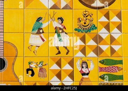 Lissabon, Portugal - 21 Nov 2019: Traditionelle Azulejo-Fliesen auf einem Gebäude im Stadtzentrum von Lissabon. Hell und lebhaft in Gelb mit tanzenden Menschen. Glücklich Stockfoto