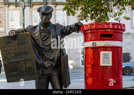 Porto, Portugal - 16th. November 2019: Die Bronzeskulptur des Zeitungsherstellers stand neben dem roten britischen Briefkasten auf dem Unabhängigkeitsplatz. Tourismus, besuchen Stockfoto