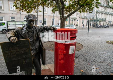Porto, Portugal - 16th. November 2019: Die Bronzeskulptur des Zeitungsherstellers stand neben dem roten britischen Briefkasten auf dem Unabhängigkeitsplatz. Tourismus, besuchen Stockfoto