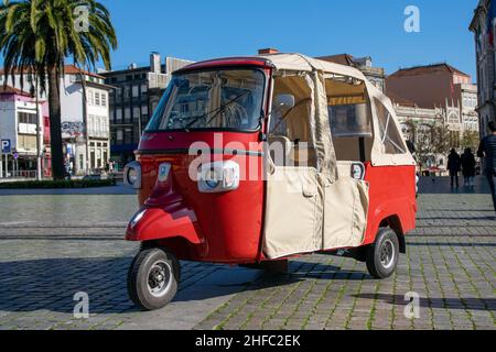 Niedliches rotes Tuk Tuk im Stadtzentrum von Porto, Portugal. Traditionelle dreirädrige Fahrzeuge transportieren Touristen zu allen wichtigen Attraktionen für einen günstigen Preis. Stockfoto