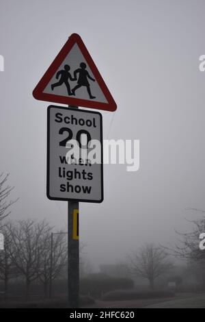 Warnschild warnt vor einer Geschwindigkeitsbegrenzung von 20 km/h. „Schule 20, wenn die Lichter leuchten.“ Stockfoto