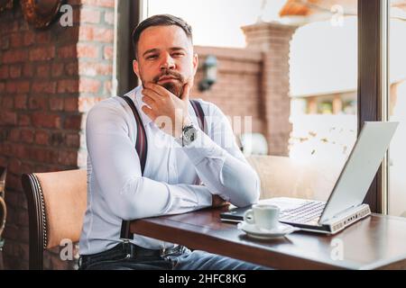 Porträt eines jungen Geschäftsmannes, der in einem Café an einem Laptop arbeitet Stockfoto