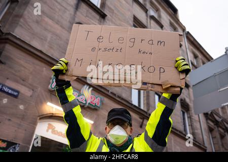 Furth, Deutschland. 15th Januar 2022. 15. Januar 2022, Bayern, Fürth: Ein Gegendemonstrator hält den Teilnehmern einer Demonstration gegen die Corona-Maßnahmen ein Schild mit der Aufschrift "Telegram ersetzt kein Mikroskop" hoch. Wissenschaft rockt!“ Foto: Stringer/dpa Kredit: dpa picture Alliance/Alamy Live News Stockfoto