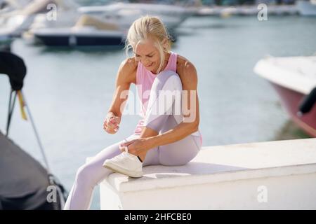 Ältere Frau, die Schnürsenkel bindet und sich auf die Fitness vorbereitet. Stockfoto