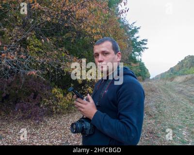 Mann mit einer Kamera auf einem Hintergrund von Bäumen Stockfoto