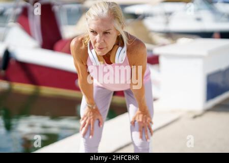 Ältere Frau in Fitnesskleidung, die ihre Arme nach dem Training streckt. Stockfoto