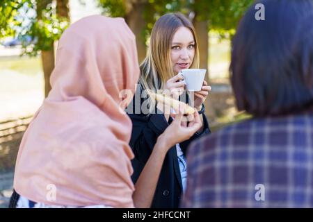 Junge Freundinnen plaudern und trinken Kaffee im Parkcafe Stockfoto