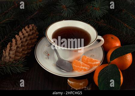 Tasse Tee mit Mandarinen und Christbaumzweigen. Dunkler Hintergrund. Stockfoto