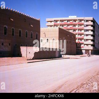 1960er Jahre, historisch, eine leere Seitenstraße in Dschidda, Saudi-Arabien, mit einem modernen Wohnblock und traditionelleren arabischen Gebäuden. Stockfoto