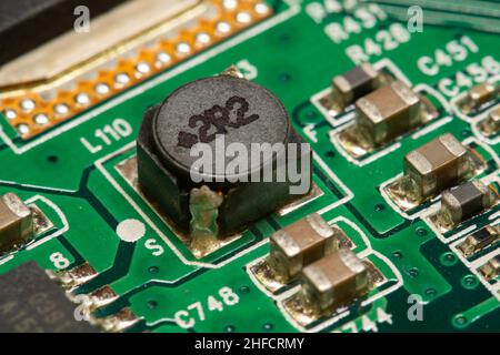 SMD-Induktivität und andere elektronische Bauteile, die auf einer grünen Leiterplatte (PCB) gelötet sind. Stockfoto