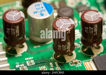 Elektrolytkondensatoren, die auf einer grünen Leiterplatte (PCB) gelötet sind. Stockfoto