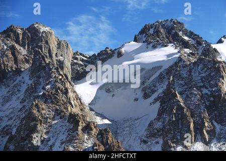 Alpine felsige schneebedeckte Gipfel mit Tuyuk Su Gletscher im Winter bei sonnigem Wetter Stockfoto