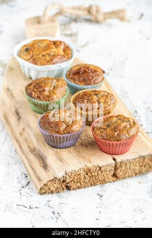 Hausgemachte gesunde Muffin-Kuchen in bunten Silikonformen auf weißem Tisch oder Hintergrund. Gluten- und zuckerfreie kleine Kuchen mit Obst auf Holzschnitt Stockfoto