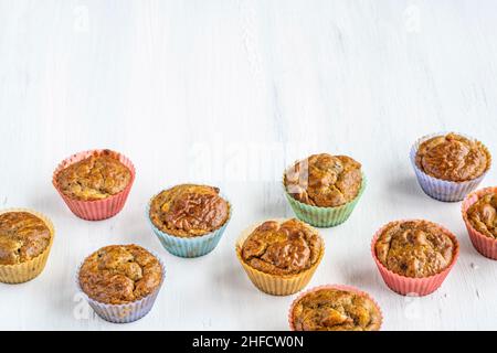 Seite oder Profil Ansicht hausgemachte Muffins in bunten Silikonformen auf weißem Tisch oder Hintergrund. Gluten und zuckerfrei kleine gesunde Kuchen mit Obst. f Stockfoto