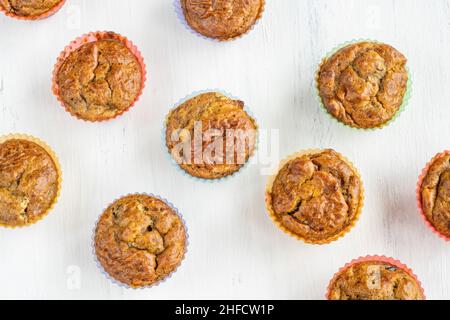 Draufsicht hausgemachte Muffins in bunten Silikonformen auf weißem Tisch oder Hintergrund. Gluten- und zuckerfrei kleine gesunde Kuchen mit Obst. Lebensmittelkonzept Stockfoto