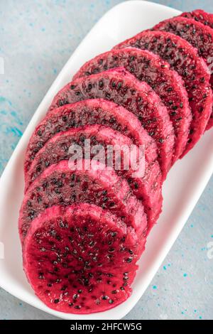 drachenfrucht, Nahaufnahme Draufsicht geschnitten rötlich rosa Drachenfrucht in weißen Teller mit selektivem Fokus. Gesundes Essen Konzept Foto Stockfoto