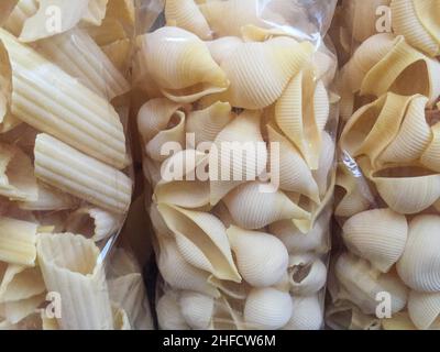 Verschiedene Formen von roher Pasta in einer transparenten Plastiktüte. Handgemachte Makkaroni in Beuteln mit selektivem Fokus. Traditionelle italienische Speisen in Packungen bei Marke Stockfoto