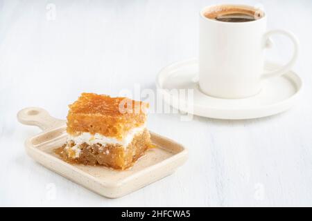 tasse türkischer Kaffee und traditionelles Dessert mit Creme, bekannt als 'ekmek kadayifi' auf Türkisch, Türkei. Berühmte traditionelle Süßspeisen, Kuchen mit Sirup Stockfoto