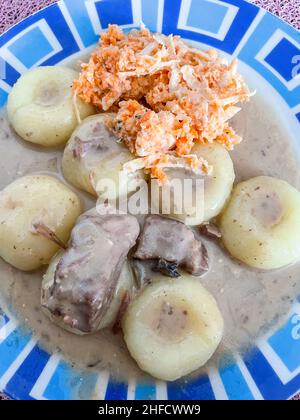 Polnische Dampfhefeknödel oder kluski na Parze können mit Fleisch und Soße oder in Butter sautiert und mit Zucker zum Dessert bestreut serviert werden. Stockfoto