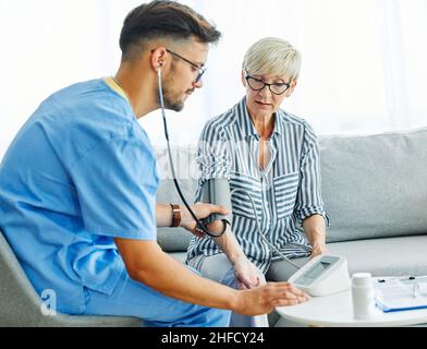 Krankenschwester Arzt Senior care Betreuer Hilfe überprüfen Untersuchung Blutdruck überprüfen Puls Ruhestand Haus Stethoskop Pflege ältere Mann Frau Gesundheit Stockfoto