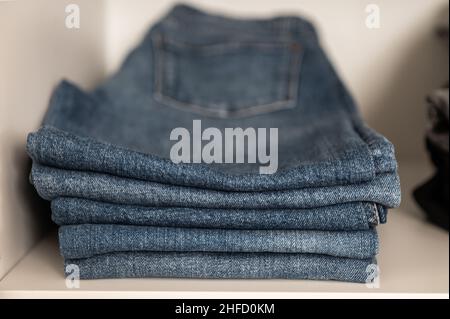 Nahaufnahme eines Stapels von ordentlich gefalteten blauen Jeans im Regal im Kleiderschrank Stockfoto