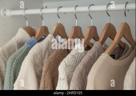 Warmer Winterpullover aus beigefarbener Wolle und Strickmode, die im Kleiderschrank hängen Stockfoto