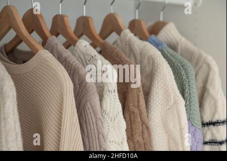 Warmer Winterpullover aus beigefarbener Wolle und Strickmode, die im Kleiderschrank hängen Stockfoto