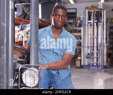 Glücklicher Arbeiter auf dem Gabelstapler im Baumarkt Stockfoto