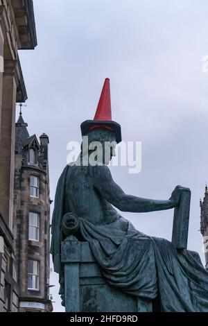 Die Statue des schottischen Philosophen David Hume auf der Royal Mile in Edinburgh, mit einem roten Verkehrskegel auf dem Kopf Stockfoto