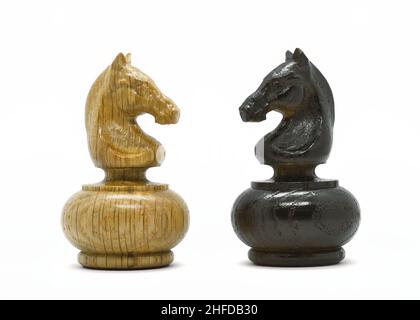 Weiße und schwarze Schachritter stehen einander auf weißem Hintergrund gegenüber. Schachfiguren aus Holz. Stockfoto