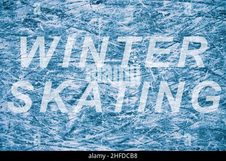 Blaue Eisstruktur. Skate-Spuren auf dem Eis. Schlittschuhlaufen im Winter. Text Winterskaten auf der Eisfläche. Abstrakter Hintergrund. Stockfoto
