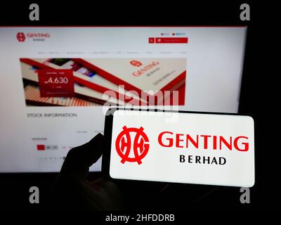 Person, die das Smartphone mit dem Logo des malaysischen Konglomerats Genting Group auf dem Bildschirm vor der Website hält. Konzentrieren Sie sich auf die Telefonanzeige. Stockfoto