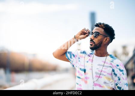 Porträt eines schwarzen Mannes, der seine Sonnenbrille mit der Hand hält Stockfoto