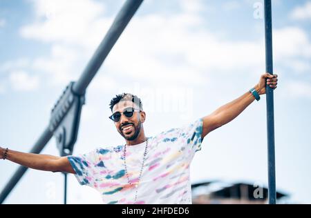 Lächelnder schwarzer Mann in Sonnenbrille erfreut sich mit ausgestreckten Armen und genießt den Moment Stockfoto