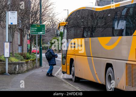 ELGIN, MORAY, SCHOTTLAND - 12. JANUAR 2022: Diese Frau ist dabei, am 12. Januar an einer Bushaltestelle auf der West Road, Elgin, Moray, Schottland an Bord eines Stagecoach-Busses zu gehen Stockfoto