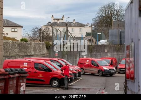 ELGIN, MORAY, SCHOTTLAND - 12. JANUAR 2022: Dies ist eine Postarbeiterin, die ihren Lieferwagen auf dem Parkplatz des Royal Mail Delivery Office, High Street, Elg reinigt Stockfoto