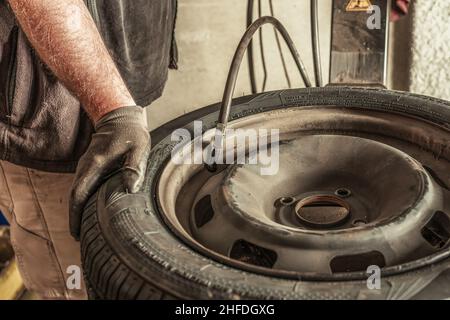 Nahaufnahme eines Mechanikers, der einen Reifen mit einem automatischen Werkzeug aufbläst Stockfoto