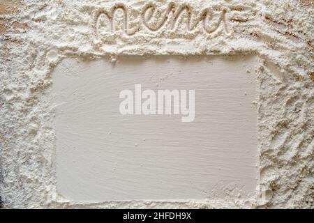 Mehl wird auf einem Holztisch mit einer handschriftlichen Inschrift - Menü und mit einem glatten rechteckigen Aufdruck bestreut. Speicherplatz kopieren. Draufsicht. Stockfoto